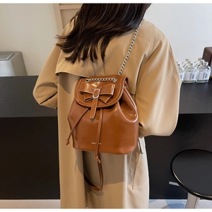 Close-up of vintage brown leather backpack with silver chain straps and bow detail