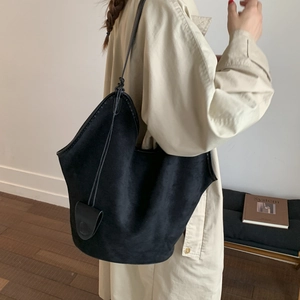 Close-up of black suede oversized tote bag featuring a decorative teardrop leather charm