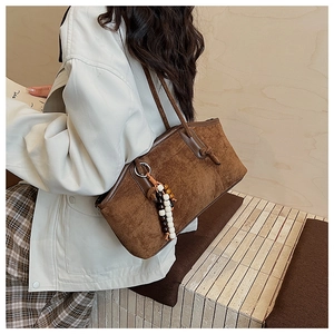 Detailansicht der braunen Wildledertasche mit Holzperlen-Anhänger und Metallring-Verbindung