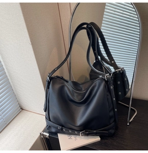 Close-up of black lychee grain leather tote with metal eyelets and decorative buckles