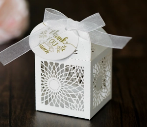 Close-up of laser-cut sunflower pattern on white gift box with ribbon and thank you tag