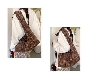 Detail of a large brown plaid canvas tote bag showing the front pocket and strap