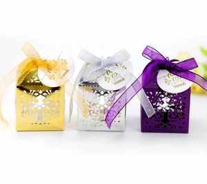 Detailed view of hollow cut candy boxes in gold, silver, and purple with organza ribbons