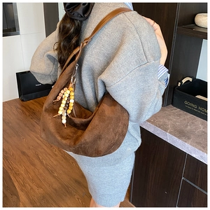 Brown suede hobo shoulder bag with colorful wooden beads shown in a modern interior setting