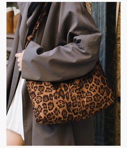 Gros plan d'un sac cabas léopard porté avec un trench gris pour un look d'hiver chic