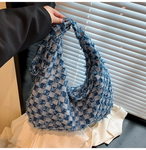 Detail of blue and white checkered denim hobo bag with vintage frayed edges in natural light