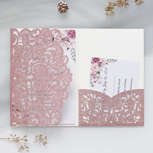 Close-up of pink glitter laser-cut wedding invitation with elegant floral insert card