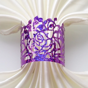 Detail of purple glitter rose cutout napkin ring on white silk fabric for wedding decor