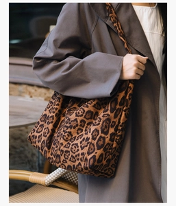 Grand sac à main léopard porté avec un trench-coat marron dans un café en plein air