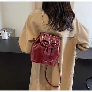 Detail shot of a burgundy patent leather bucket backpack with a large bow on the back