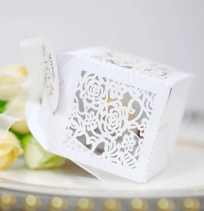 Detailed laser-cut rose hollow favor box with white satin ribbon and gold tag for weddings