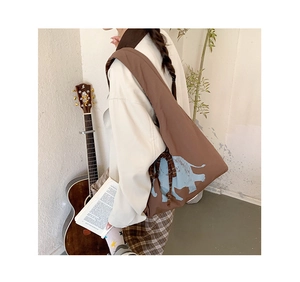 Brown canvas tote bag with blue elephant print and side ribbon detail in a cozy home setting