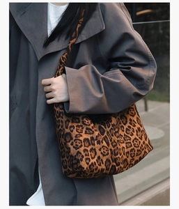 Vue street style d'un grand sac cabas à imprimé léopard porté avec un trench-coat gris