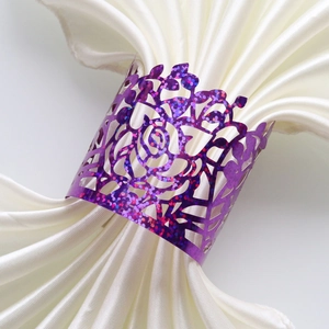 Macro shot of purple glitter laser-cut rose napkin ring on white silk fabric napkin