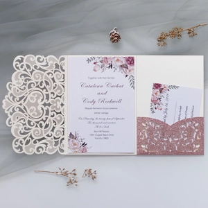 Detail of laser-cut lace wedding invitation with rose gold glitter pocket and floral insert
