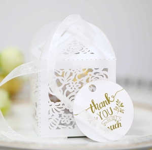 Detail of laser cut white wedding favor box with thank you tag and chiffon ribbon