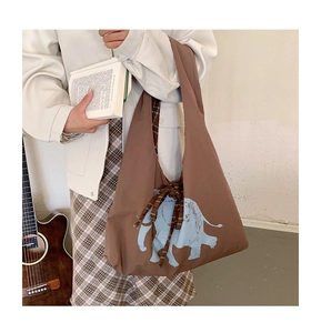 Detail of artistic elephant print and plaid drawstring on a brown canvas tote bag