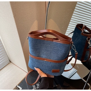 Detail of denim bucket bag with brown leather trim and high-quality stitching texture