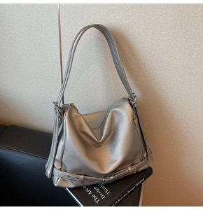 Detail of silver pebble grain leather tote bag with metallic texture and buckle strap