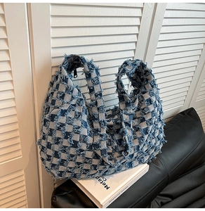 Close-up of blue and white checkerboard denim tote bag with stylish frayed fringe edges