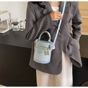 Detail of light blue woven bucket bag with silk scarf handle and gold charms