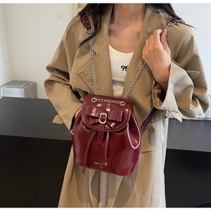 Detail of dark red patent leather mini backpack with silver chain strap and bow