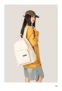 Close-up detail of white canvas backpack featuring front zipper pocket and brand label