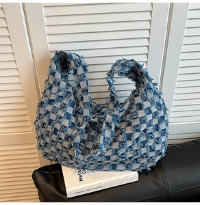 Detail of blue and white checkered denim tote bag with stylish frayed fringe edges