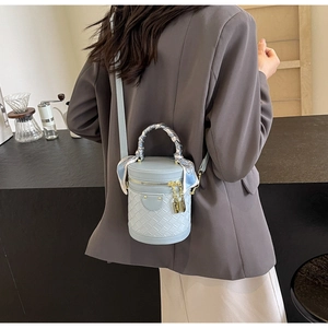Close-up of light blue bucket bag featuring woven pattern and printed silk scarf handle