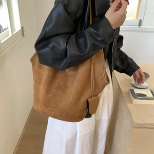 Close-up of brown suede tote bag with matching coin purse worn on the shoulder
