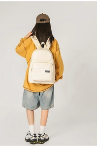 Detailed view of cream canvas backpack with BOGEWADE logo worn by female student