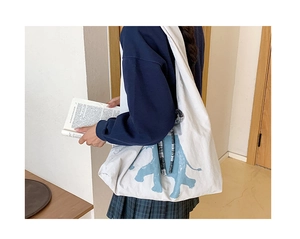 Detailed side view of white canvas tote bag with elephant print and checkered strap