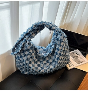 Detailed view of frayed edges on blue and white checkered denim tote bag with zipper