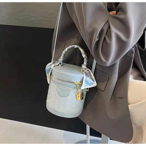 Detail of light blue bucket bag with woven base, silk scarf handle and metal lock