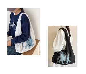 Detail of canvas tote bags in black and cream featuring elephant prints and plaid bows