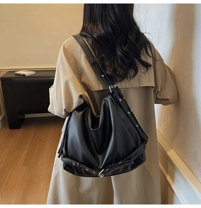 Black pebbled leather hobo bag with silver eyelets shown on model for capacity
