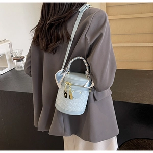Detail of light blue woven bucket bag with floral scarf handle and gold hardware lock