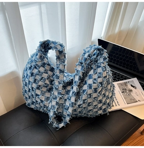 Detail shot of distressed blue and beige checkered denim tote with fringe textures
