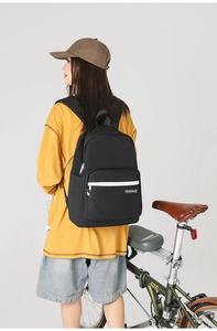 Close-up of black canvas backpack with white contrast zipper and branded woven label