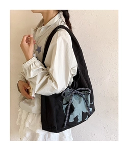 Detail of black canvas tote bag featuring a blue elephant print and plaid bow accessory