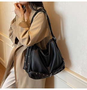 Close-up of black leather tote bag featuring silver eyelets and rivets in hobo style