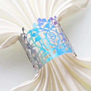 Detailed macro view of laser-cut iridescent metal napkin ring with rose flower pattern