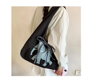 Detail of a black canvas tote featuring a light blue elephant print and checkered bow ribbon