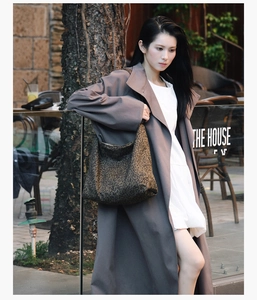 Sac hobo chic à imprimé léopard porté avec un trench-coat gris dans un cadre urbain