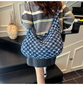 Detail of blue and white checkered crescent tote bag with fringe edges and retro style