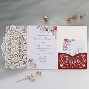 Detailed laser-cut cream lace wedding invitation set with floral inserts and red glitter