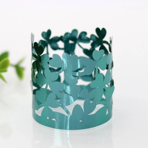 Dettaglio del portatovagliolo verde metallizzato con motivi a trifoglio e cuori