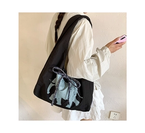 Detail of canvas tote bag showing blue elephant print and gingham ribbon bow detail