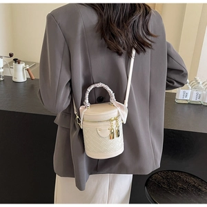 Detail of cream white bucket bag featuring woven pattern and silk ribbon handle