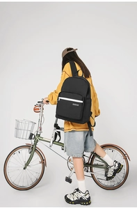 Side view of black minimalist backpack on model featuring front zip pocket and water bottle slot